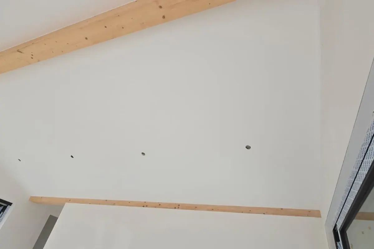 Pièce sous combles finie, plâtre blanc lissé et poutres en bois apparentes